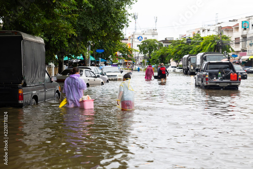 Asian boy wearing Raincoat and mother waded through floodwaters to go buy food, lifestyle of Thai people in massive flooding, Severe weather