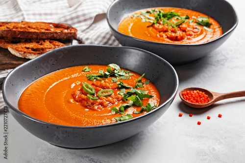Red lentil soup in gray bowl with toasted bread, side view