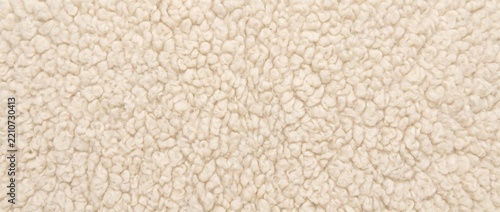 Sherpa fleece curly texture background. Close up of soft beige wool shearling fabric. Cozy fluffy textile backdrop