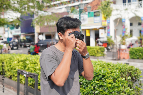 Asian Tourist Man Taking Photo with Camera Outdoors in Yogyakarta City