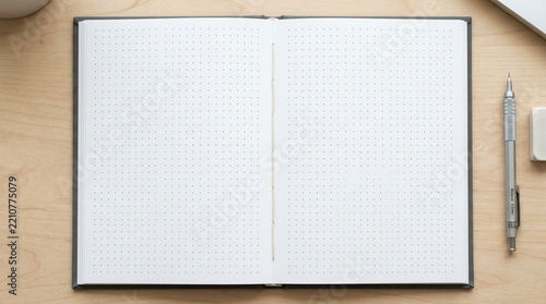 Open dot grid notebook with pen and eraser on wooden desk