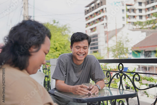 Two Friends Laughing on a Balcony