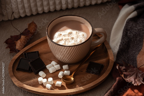 Cozy warm hot chocolate drink with marshmallows and dark chocolate squares on wooden tray cozy autumn comfort concept