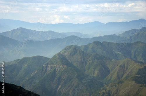 Scenic daytime view of lush green mountain slopes and distant hazy ridges in Mussoorie
