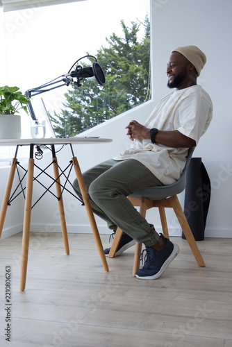 African American man wearing beanie recording in home studio with boom mic pop filter, copy space