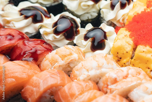 A close-up of a selection of various sushi rolls with caviar, cream cheese, unagi sauce, salmon, and shrimp
