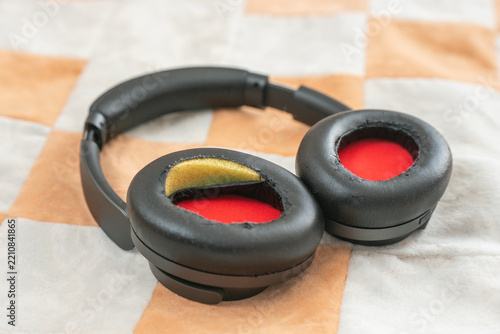 A close-up of headphones with damaged ear pads and worn eco-leather