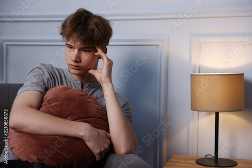 Obraz na plátně Teenage boy with cushion suffering from stress at home