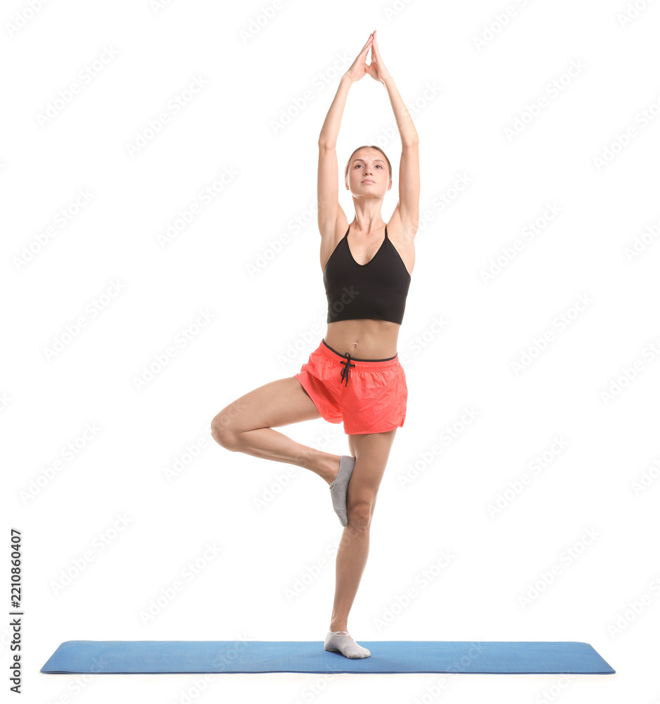 Naklejka premium Young woman practicing yoga on fitness mat against white background