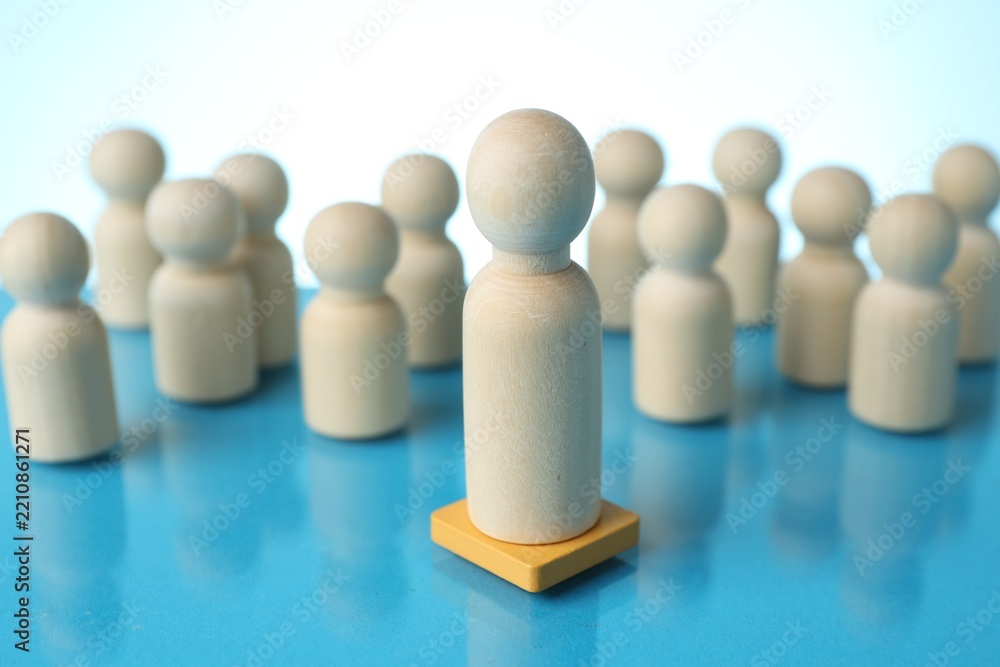 Obraz premium Competition concept. Big human figure among smaller ones on mirror table against light blue gradient background, closeup