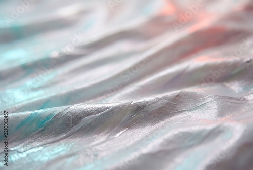 Close up of an abstract iridescent folded texture with soft pastel reflections and shallow depth of field