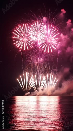 Fireworks display over the water during night showing bright colors and sparks in the sky