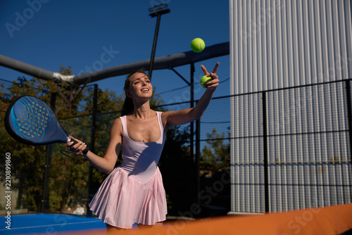 Fotografie Young female athlete hitting a padel ball on a blue outdoor court