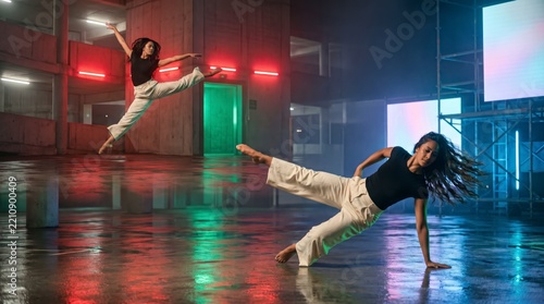 Agile dancer in airborne split leap and floor spin inside concrete parking garage with neon glow