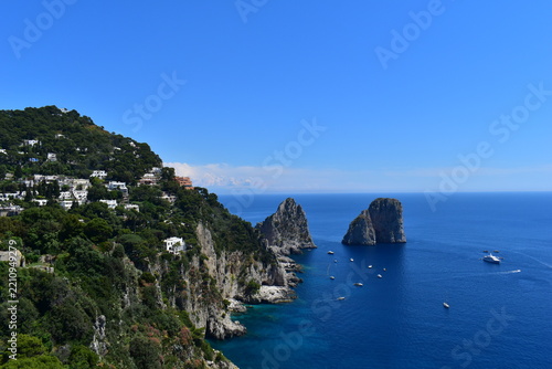 Beautiful landscape of Capri island with blue Tyrrhenian sea, boats and Faraglioni stacks