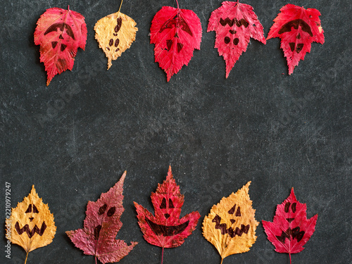 Halloween double side border of spooky autumn red and yellow leaves ghosts. Overhead view on a black background. Creative evil Halloween template. Top view, flat lay, copy space