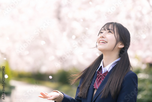 満開の桜を見上げて笑顔を見せる日本人女子高校生