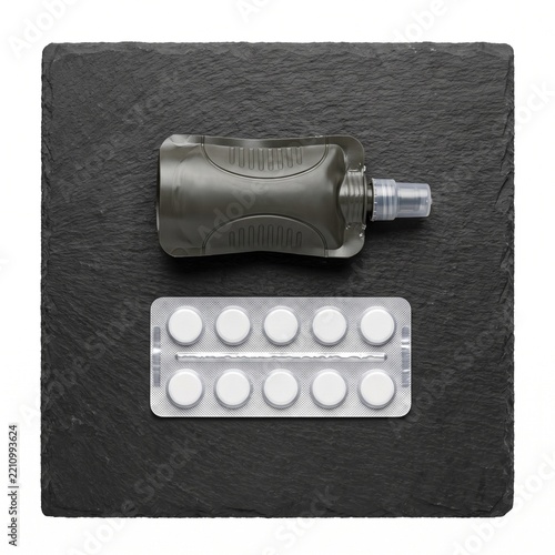 Energy Gel Pouch and Pills Blister Pack on Slate Board Isolated on White Background - Sports Nutrition and Medical Supplements Flat Lay