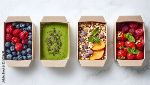 Fresh yogurt parfaits in paper cups topped with fruit, granola, berries.

