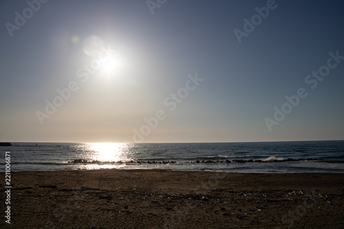 夕暮れの海を照らす太陽と砂浜