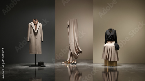 Fashion display featuring mannequins with beige coats and pleated skirts in a minimalist studio