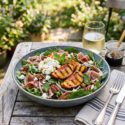 Grilled peach salad with greens and wine served on rustic wooden