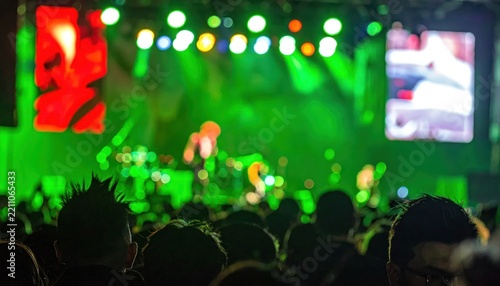 Enthusiastic crowd at music festival with green stage lighting.