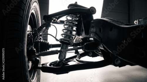Close up of modern car suspension system featuring coilover shock absorber and control arm with precision engineering for automotive repair services and performance tuning marketing.