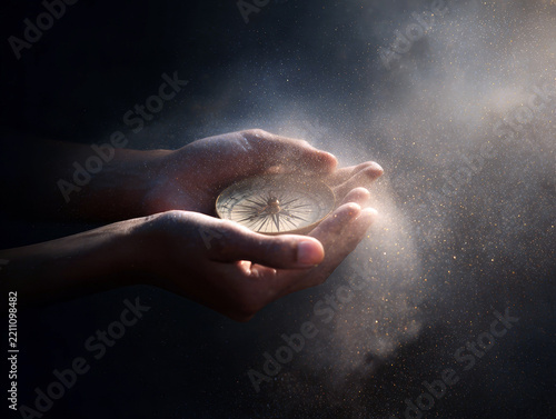 Hands cradling a glowing compass on a dark cosmic background for spiritual guidance poster or wallpaper design