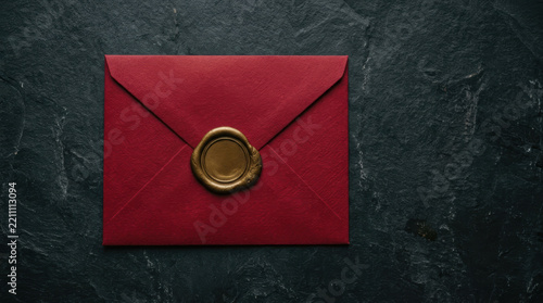 Red envelope with gold wax seal on dark textured surface festive background for invitation or greeting card with elegant style