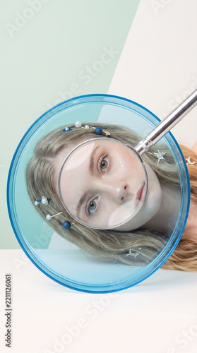Creative portrait of young woman with magnifying glass
