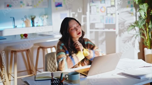 Asian freelancer video call laptop home office. Woman gesturing explaining work.