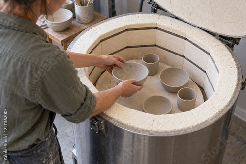 Potter loading an unglazed bowl into a cold pottery kiln