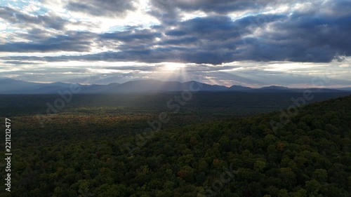 Sun rays shine over a vast forest and mountains, Maine.