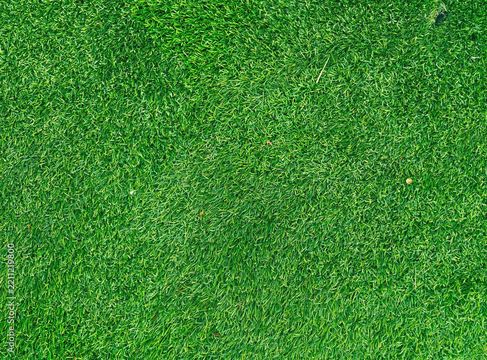 Fototapeta premium Detailed synthetic green grass turf texture background showing dense plastic fibers and artificial lawn surface pattern structure