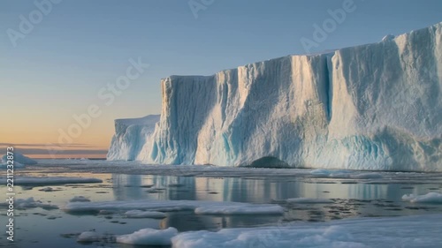 Majestic icebergs drift in calm arctic ocean during golden hour sunset cinematic motion