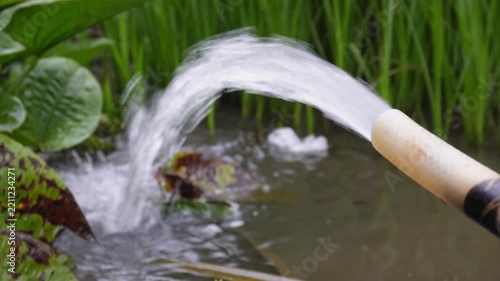 Water pumping from a hose into a lush green field irrigation system.