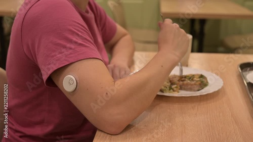 A woman with a continuous glucose monitor is eating in a cafe. 