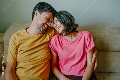 Happy husband and wife share love on the couch indoors