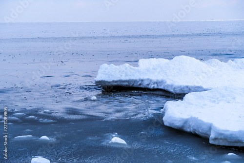 Icebergs floating on calm blue water under a cloudy sky