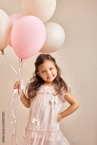Little girl smiling, holding pink and white balloons