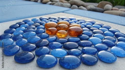 Vibrant cobalt blue and amber glass pebbles arranged in a smooth, scattered pattern