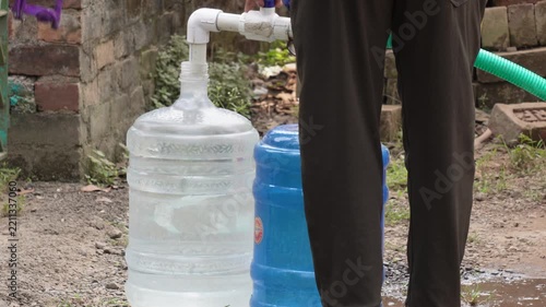 Large 20-Liter Plastic Water Carboys Being Filled Outdoors