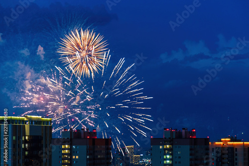 Bright long fireworks exploding over urban apartment buildings at night. Ideal for New Year and festive city celebration concepts