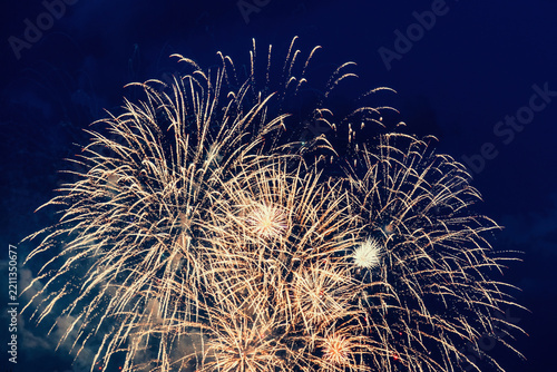 Bright golden fireworks burst against a dark blue sky. Ideal for festive holiday celebrations, New Year Eve parties, and grand events