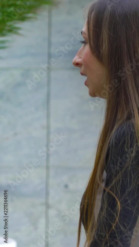 Young woman with long hair talking and gesturing with hands outdoors, expressing emotion and engagement during friendly conversation