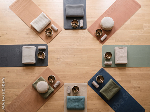 Top-down group sound bath setup with folded blankets, cushions and bowls on parquet