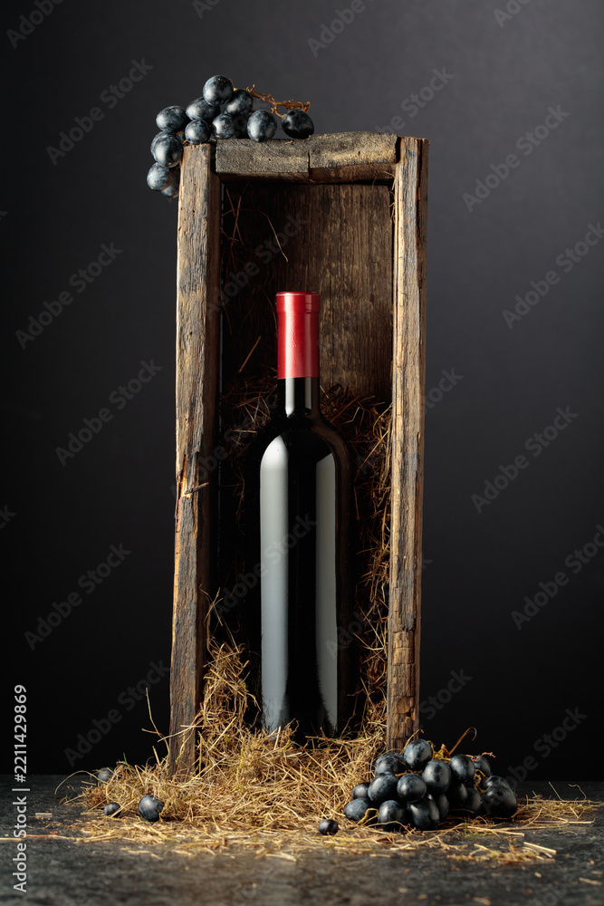 Obraz premium Bottle of red wine in old wooden box on a black background.