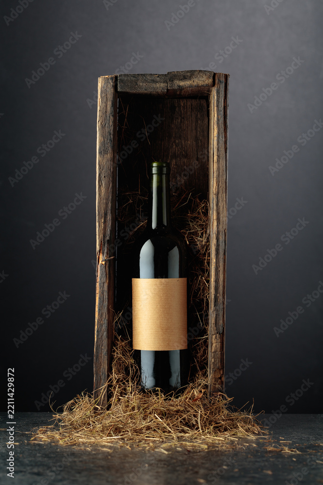Obraz premium Bottle of red wine in old wooden box on a black background.