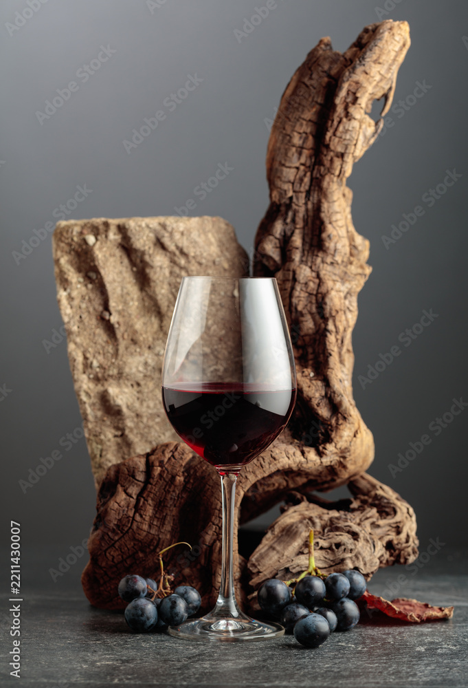 Obraz premium Red wine with stone, dried snags, and blue grapes.